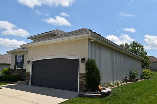 2015 Creek View Ln, Raymore, MO 64083 - view of side of home featuring concrete driveway, stone siding, an attached garage, a lawn, and stucco siding
