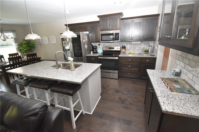 2015 Creek View Ln, Raymore, MO 64083 - kitchen with stainless steel appliances, dark brown cabinets, decorative backsplash, and a breakfast bar