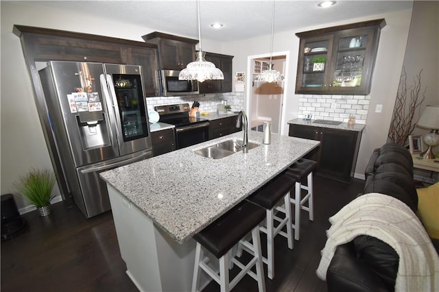 2015 Creek View Ln, Raymore, MO 64083 - kitchen with appliances with stainless steel finishes, backsplash, a breakfast bar area, glass insert cabinets, and dark brown cabinets