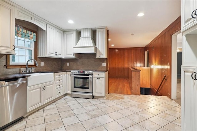 126 W 116th St, Kansas City, MO 64114 - kitchen with appliances with stainless steel finishes, custom range hood, dark countertops, backsplash, and wooden walls
