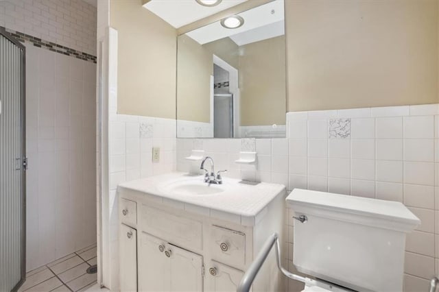126 W 116th St, Kansas City, MO 64114 - full bath featuring vanity, tile walls, a shower with shower door, tile patterned floors, and wainscoting