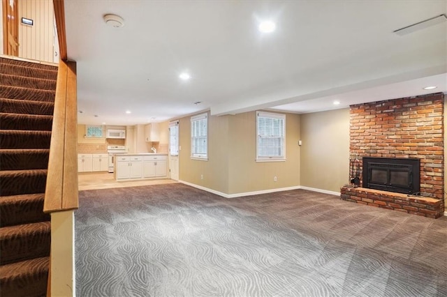 126 W 116th St, Kansas City, MO 64114 - unfurnished living room featuring light carpet, a brick fireplace, stairway, and recessed lighting
