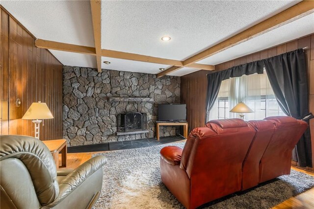 9714 Shepherds Dr, Kansas City, MO 64131 - living area featuring wood walls, beam ceiling, a fireplace, and a textured ceiling