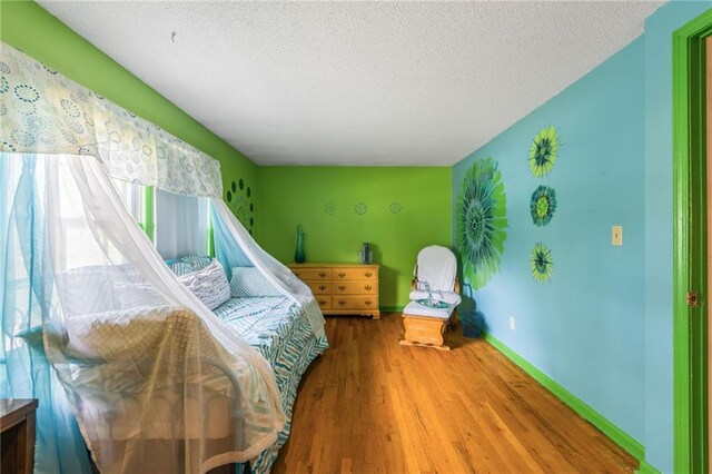 9714 Shepherds Dr, Kansas City, MO 64131 - bedroom featuring wood finished floors, a textured ceiling, and baseboards