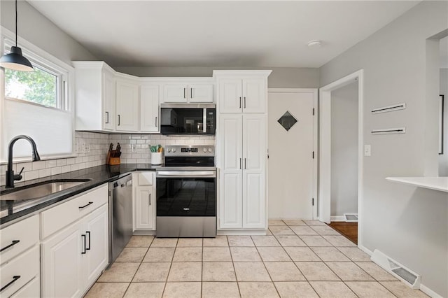 10417 Outlook Dr, Overland Park, KS 66207 - kitchen with stainless steel appliances, backsplash, dark countertops, and white cabinetry