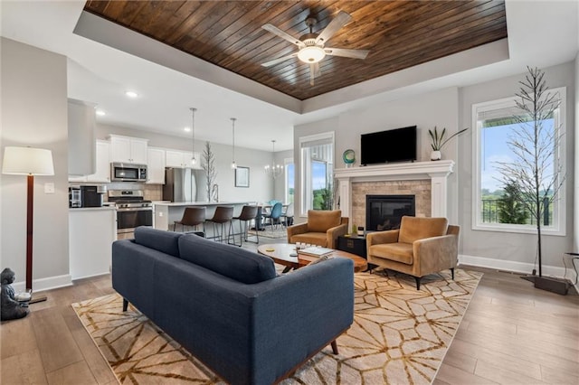 9504 N Amoret Ave, Kansas City, MO 64154 - living area with a tray ceiling, wooden ceiling, baseboards, light wood-style flooring, and plenty of natural light