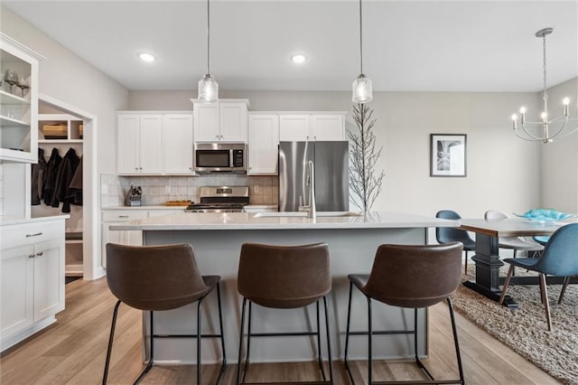 9504 N Amoret Ave, Kansas City, MO 64154 - kitchen featuring stainless steel appliances, a breakfast bar area, a center island with sink, light wood finished floors, and recessed lighting