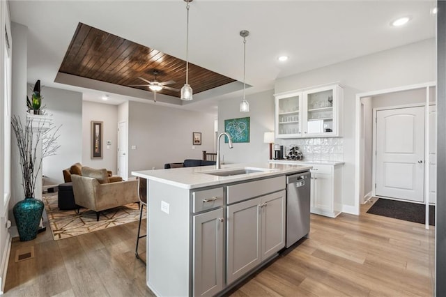 9504 N Amoret Ave, Kansas City, MO 64154 - kitchen featuring stainless steel dishwasher, a raised ceiling, a sink, light wood-style floors, and open floor plan