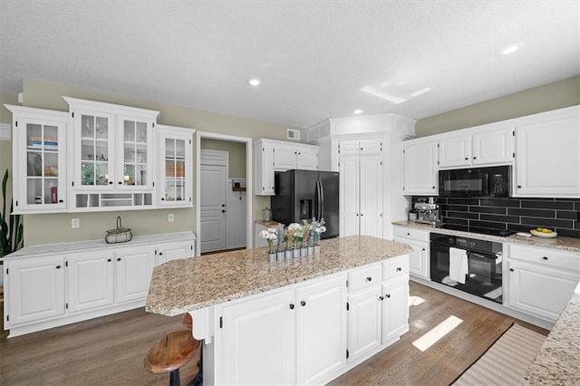 17631 S Brockway St, Olathe, KS 66062 - kitchen featuring black appliances, a center island, dark wood-type flooring, white cabinets, and glass insert cabinets
