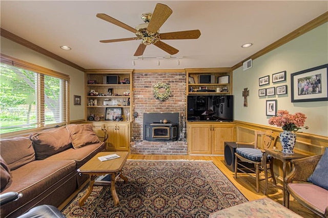 301 W 109th St, Kansas City, MO 64114 - living area featuring a wood stove, light wood-type flooring, ceiling fan, crown molding, and built in shelves