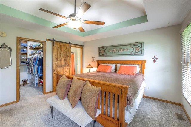 210 SE 200th Rd, Clinton, MO 64735 - bedroom with a barn door, carpet, baseboards, a walk in closet, and ceiling fan