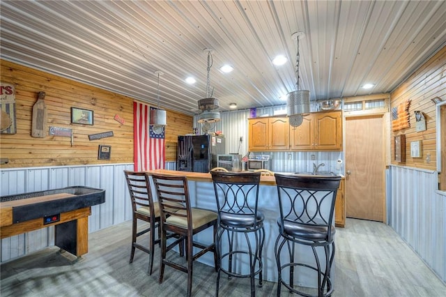 210 SE 200th Rd, Clinton, MO 64735 - kitchen featuring black refrigerator with ice dispenser, wood walls, light wood-style flooring, a kitchen bar, and wood ceiling