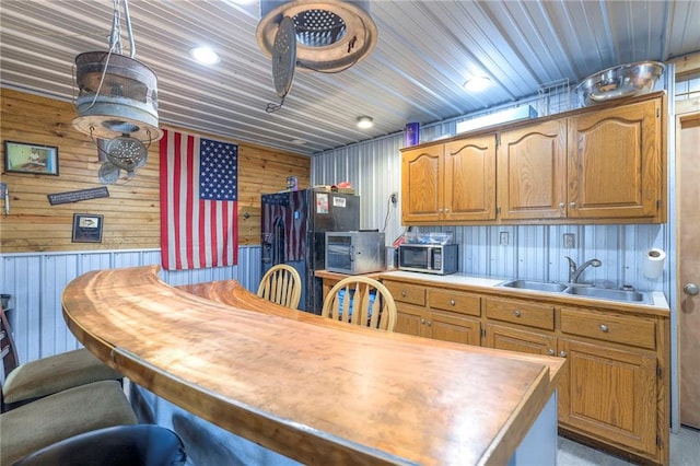 210 SE 200th Rd, Clinton, MO 64735 - kitchen featuring a sink, stainless steel microwave, wood walls, light countertops, and brown cabinetry