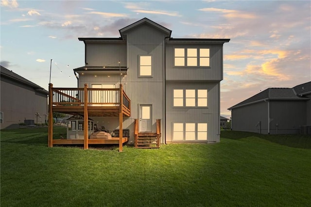 20711 W 49th St, Shawnee, KS 66218 - back of house at dusk featuring a yard, a wooden deck, and central AC