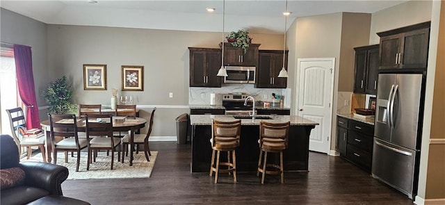 12432 Live Oak Cir, Peculiar, MO 64078 - kitchen with stainless steel appliances, decorative backsplash, dark wood-type flooring, an island with sink, and a kitchen breakfast bar