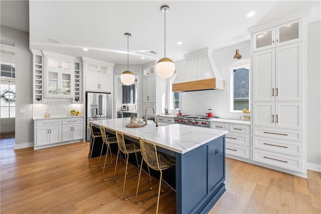9291 Brownridge St, Lenexa, KS 66220 - kitchen featuring custom range hood, stainless steel fridge with ice dispenser, a kitchen breakfast bar, light wood-style flooring, and white cabinets