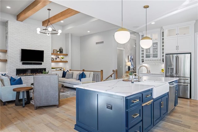 9291 Brownridge St, Lenexa, KS 66220 - kitchen with appliances with stainless steel finishes, blue cabinets, light wood-type flooring, open floor plan, and white cabinets