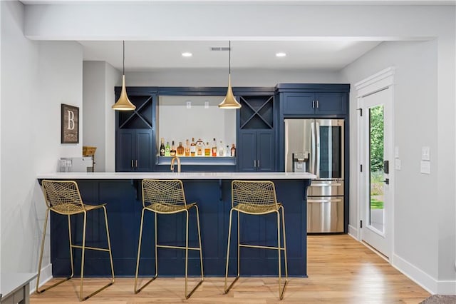 9291 Brownridge St, Lenexa, KS 66220 - kitchen featuring stainless steel fridge with ice dispenser, blue cabinets, a breakfast bar, light wood-type flooring, and hanging light fixtures