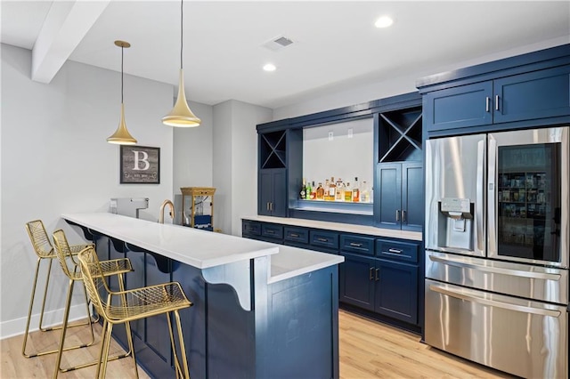 9291 Brownridge St, Lenexa, KS 66220 - kitchen with stainless steel refrigerator with ice dispenser, blue cabinetry, a kitchen bar, a peninsula, and light wood-style floors