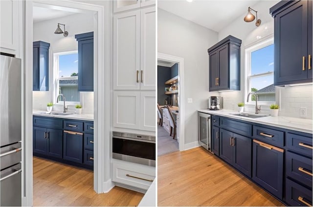 9291 Brownridge St, Lenexa, KS 66220 - kitchen featuring freestanding refrigerator, blue cabinets, light wood-style floors, and plenty of natural light