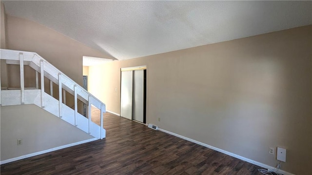 8476 Lane Dr, Raytown, MO 64138 - empty room with wood finished floors, vaulted ceiling, stairway, and a textured ceiling