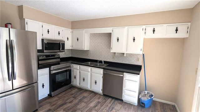 8476 Lane Dr, Raytown, MO 64138 - kitchen featuring stainless steel appliances, dark countertops, white cabinets, dark wood finished floors, and decorative backsplash