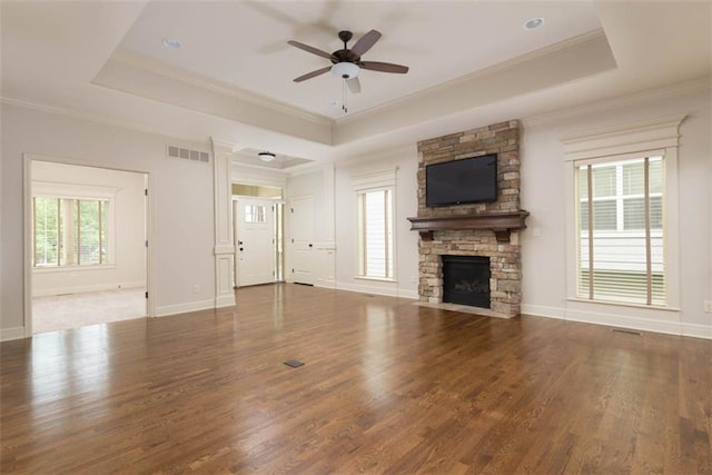 8558 Barstow St, Lenexa, KS 66219 - unfurnished living room with a raised ceiling, ceiling fan, wood finished floors, a stone fireplace, and crown molding