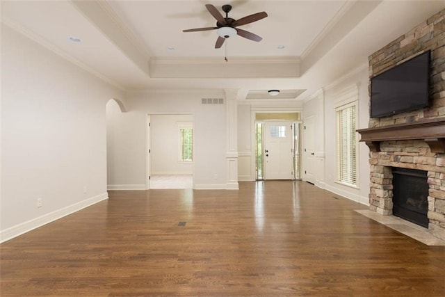 8558 Barstow St, Lenexa, KS 66219 - unfurnished living room featuring a ceiling fan, a stone fireplace, crown molding, wood finished floors, and arched walkways