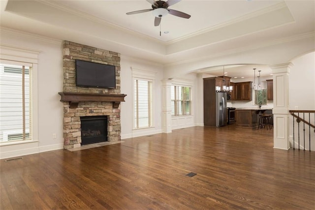 8558 Barstow St, Lenexa, KS 66219 - unfurnished living room with a chandelier, dark wood finished floors, ceiling fan, a raised ceiling, and a stone fireplace