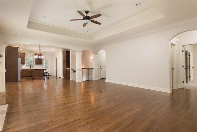 8558 Barstow St, Lenexa, KS 66219 - unfurnished living room featuring ceiling fan, dark wood-style floors, a tray ceiling, and crown molding