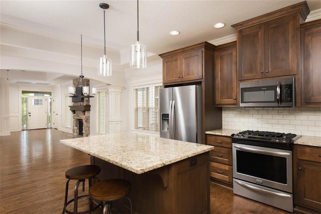 8558 Barstow St, Lenexa, KS 66219 - kitchen with stainless steel appliances, tasteful backsplash, open floor plan, dark wood finished floors, and ornate columns