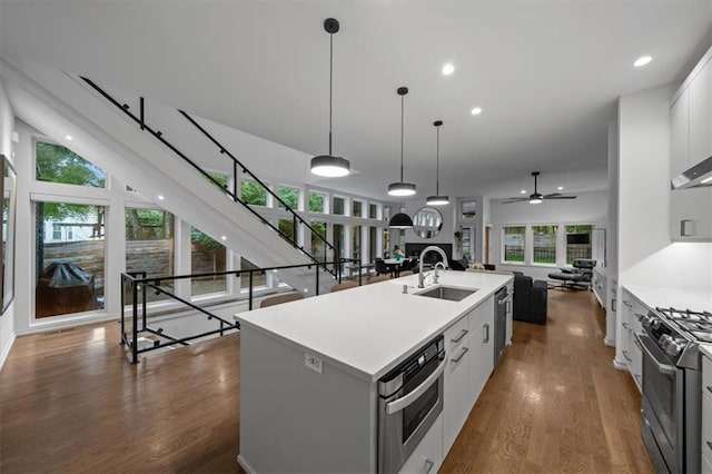 2711 W 49th St, Westwood, KS 66205 - kitchen featuring stainless steel appliances, dark wood-style floors, a sink, a center island with sink, and light countertops