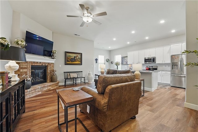7546 Mccormick Dr, Shawnee, KS 66227 - living room featuring light wood-style floors, a ceiling fan, a fireplace, and recessed lighting