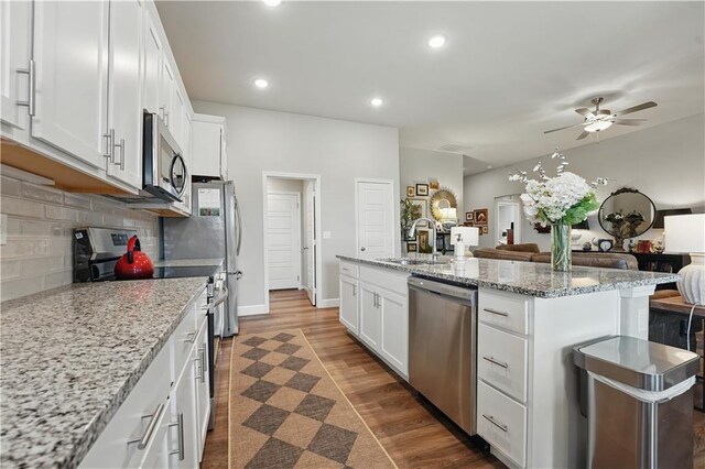 7546 Mccormick Dr, Shawnee, KS 66227 - kitchen with appliances with stainless steel finishes, open floor plan, a ceiling fan, white cabinetry, and tasteful backsplash