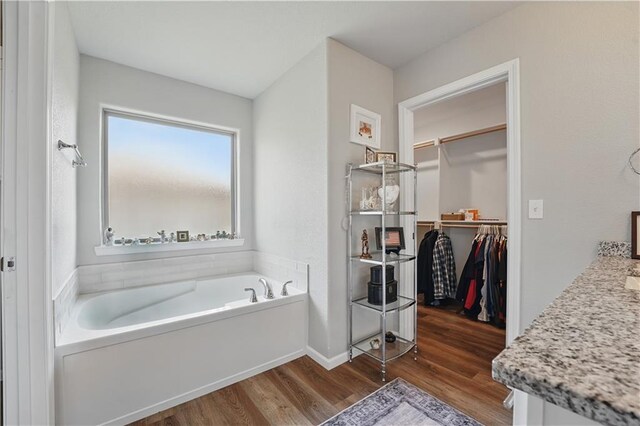 7546 Mccormick Dr, Shawnee, KS 66227 - full bathroom featuring a garden tub, wood finished floors, a spacious closet, and vanity