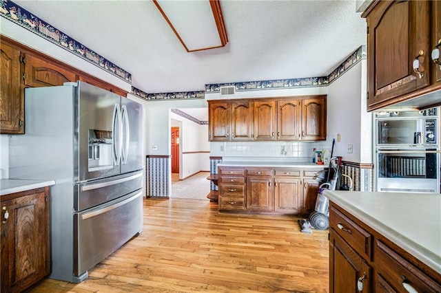 630 Oo Hwy, Centerview, MO 64019 - kitchen featuring appliances with stainless steel finishes, light wood-style floors, light countertops, tasteful backsplash, and a textured ceiling