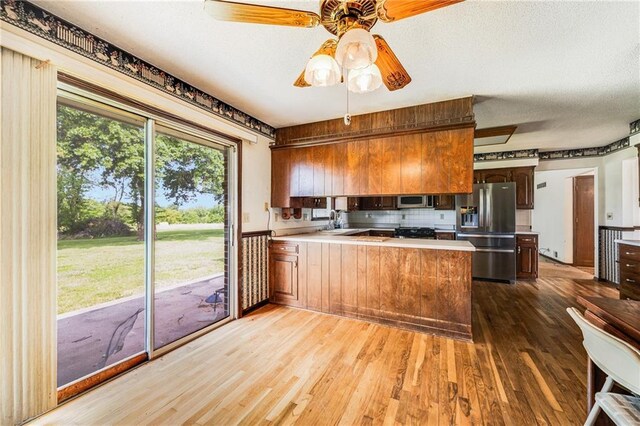 630 Oo Hwy, Centerview, MO 64019 - kitchen featuring appliances with stainless steel finishes, a peninsula, wood finished floors, a sink, and backsplash