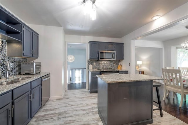14001 S Tomahawk Dr, Olathe, KS 66062 - kitchen with appliances with stainless steel finishes, tasteful backsplash, light stone counters, and light wood-style floors
