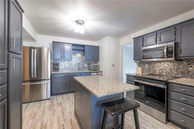 14001 S Tomahawk Dr, Olathe, KS 66062 - kitchen featuring appliances with stainless steel finishes, light wood finished floors, tasteful backsplash, a breakfast bar area, and a center island