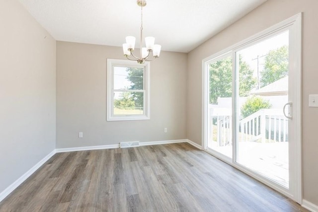 105 S W St, Concordia, MO 64020 - spare room featuring wood finished floors, a chandelier, and healthy amount of natural light
