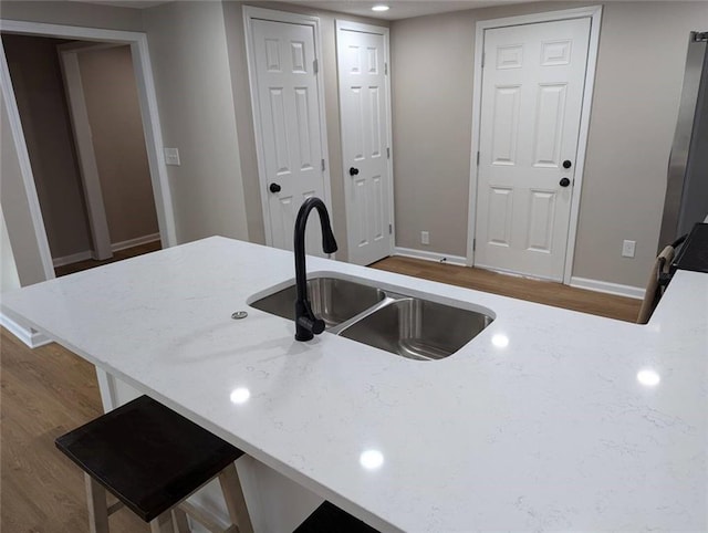 8804 E 47th St, Kansas City, MO 64129 - kitchen featuring a sink, wood finished floors, baseboards, and light stone counters