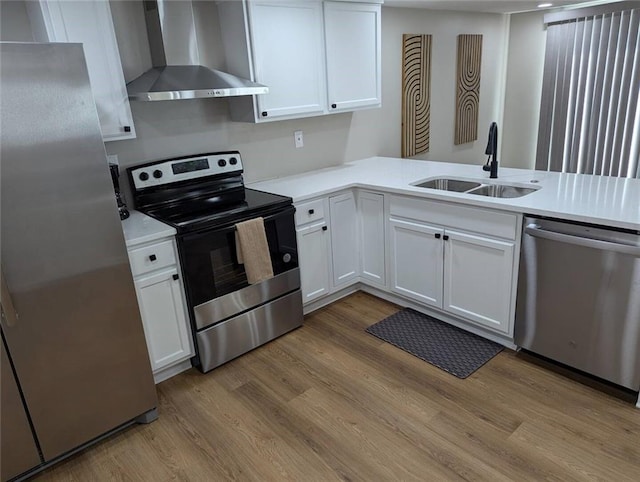 8804 E 47th St, Kansas City, MO 64129 - kitchen with wall chimney exhaust hood, appliances with stainless steel finishes, a sink, light wood finished floors, and white cabinets