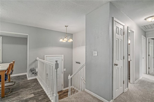 604 NE Ash St NE, Lees Summit, MO 64063 - hallway featuring an upstairs landing, a textured ceiling, a chandelier, wood finished floors, and baseboards