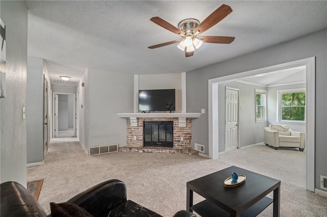 604 NE Ash St NE, Lees Summit, MO 64063 - living room featuring carpet flooring, a textured ceiling, a ceiling fan, a brick fireplace, and baseboards