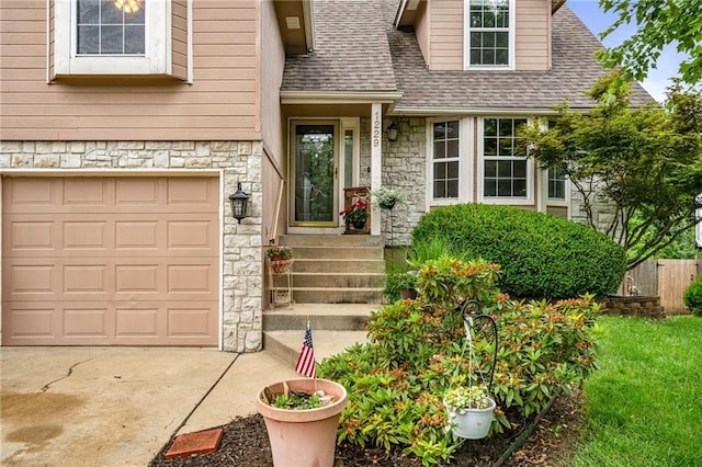 1229 SE Princeton Dr, Lees Summit, MO 64081 - property entrance featuring stone siding, an attached garage, concrete driveway, and roof with shingles