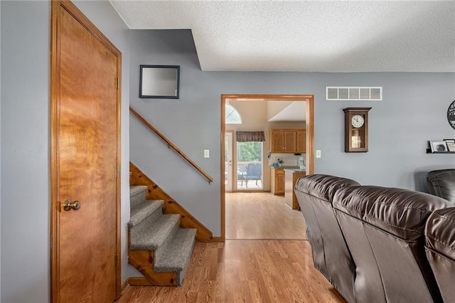 1229 SE Princeton Dr, Lees Summit, MO 64081 - living area with light wood-style flooring, stairs, and a textured ceiling