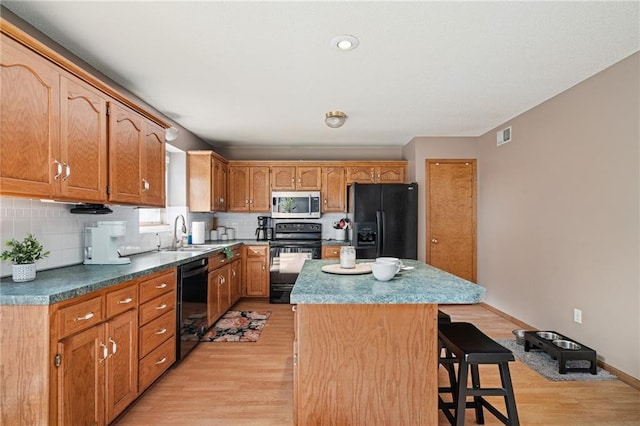 1229 SE Princeton Dr, Lees Summit, MO 64081 - kitchen featuring black appliances, light wood-type flooring, a center island, backsplash, and a breakfast bar