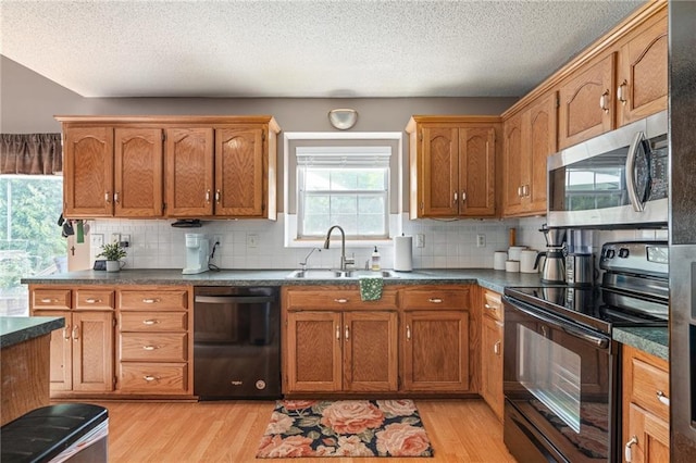 1229 SE Princeton Dr, Lees Summit, MO 64081 - kitchen with black appliances, light wood-type flooring, dark countertops, backsplash, and a textured ceiling