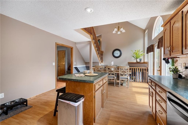 1229 SE Princeton Dr, Lees Summit, MO 64081 - kitchen with stainless steel dishwasher, dark countertops, light wood-style floors, a chandelier, and a textured ceiling