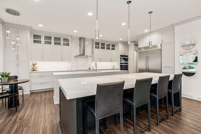 400 W 49th Ter Unit 2106, Kansas City, MO 64112 - kitchen with wall chimney range hood, stainless steel appliances, a large island, dark wood-style floors, and white cabinets